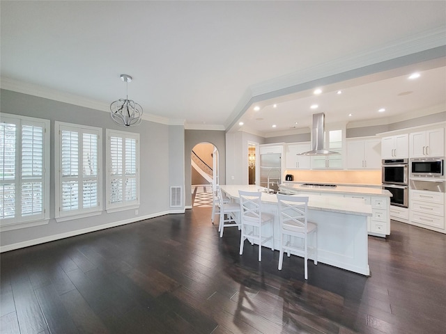 kitchen with island range hood, a center island with sink, appliances with stainless steel finishes, dark hardwood / wood-style flooring, and white cabinets