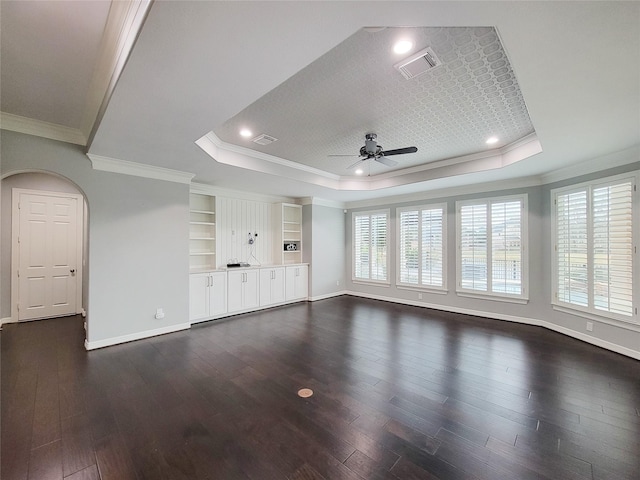 unfurnished living room featuring a raised ceiling, crown molding, dark wood-type flooring, and ceiling fan