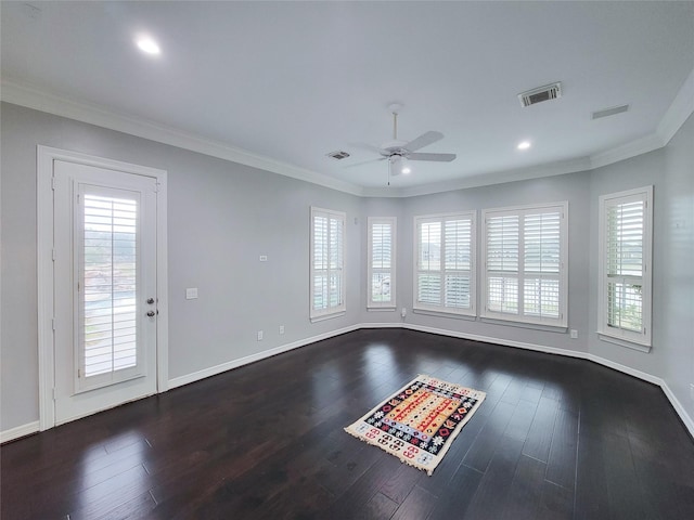 spare room featuring crown molding, dark wood-type flooring, and a wealth of natural light