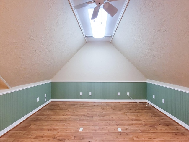 additional living space with hardwood / wood-style flooring, ceiling fan, lofted ceiling, and a textured ceiling