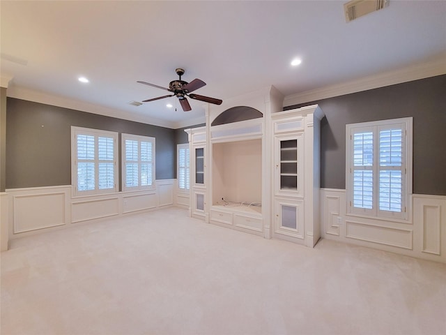 unfurnished living room with ornamental molding, carpet flooring, and ceiling fan