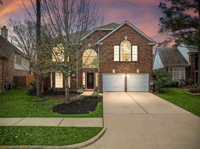 traditional home with a garage, a front yard, brick siding, and driveway