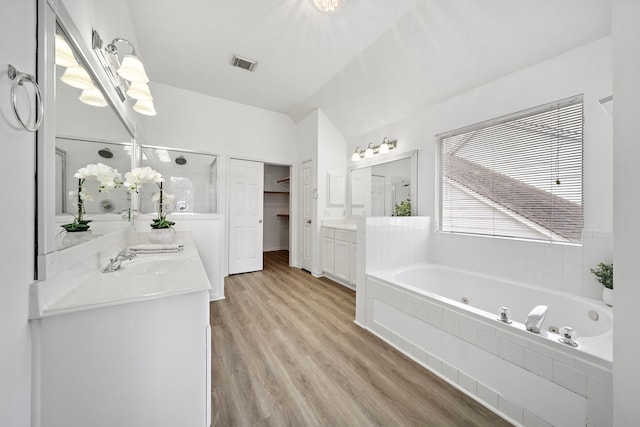 full bath with wood finished floors, vanity, visible vents, a jetted tub, and a walk in closet