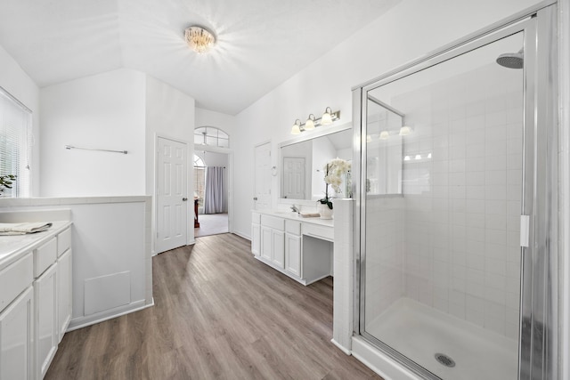 full bathroom featuring lofted ceiling, wood finished floors, vanity, and a shower stall