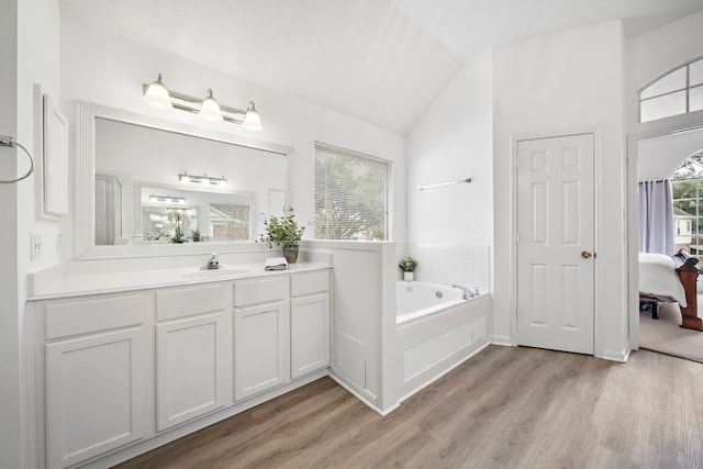 full bath with lofted ceiling, ensuite bath, wood finished floors, vanity, and a bath