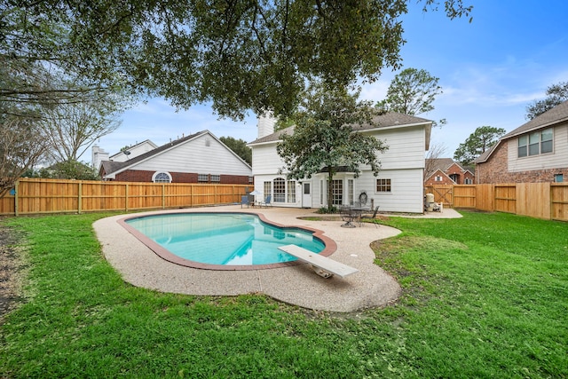 view of swimming pool with a fenced backyard, a diving board, a yard, a fenced in pool, and a patio area