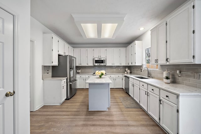 kitchen with a sink, stainless steel appliances, a kitchen island, and white cabinets