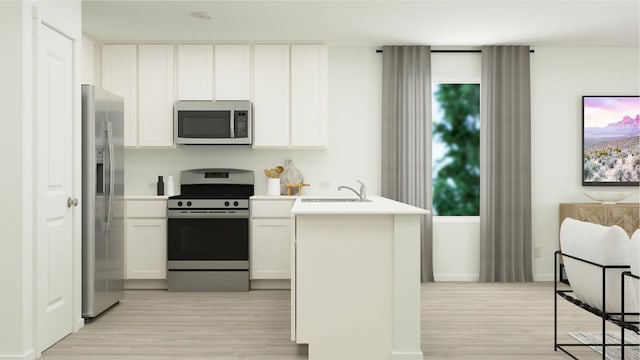 kitchen with stainless steel appliances, sink, light wood-type flooring, and white cabinets