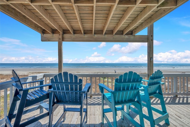 wooden deck with a water view and a beach view