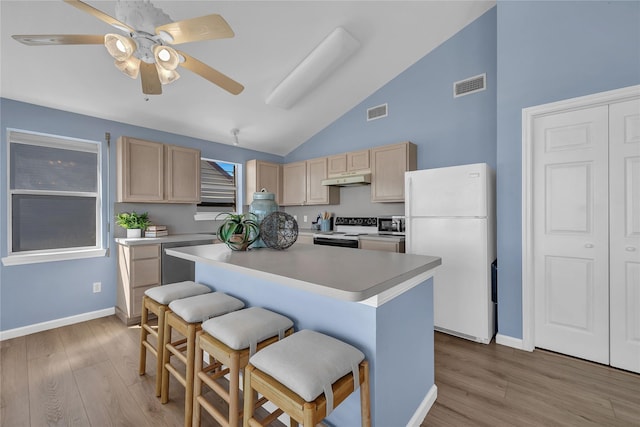 kitchen featuring a breakfast bar area, electric range oven, light brown cabinets, stainless steel dishwasher, and white fridge