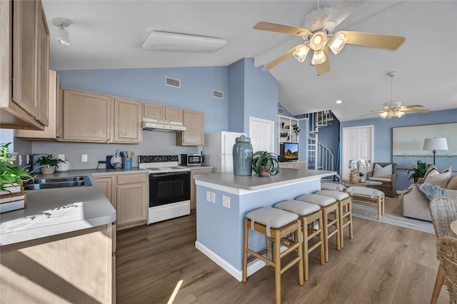 kitchen with a kitchen island, a kitchen bar, light brown cabinets, white appliances, and light hardwood / wood-style flooring