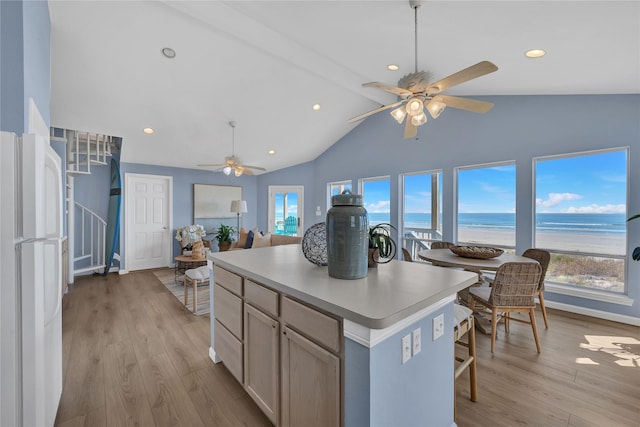 kitchen with a kitchen island, light brown cabinetry, white refrigerator, a water view, and light wood-type flooring