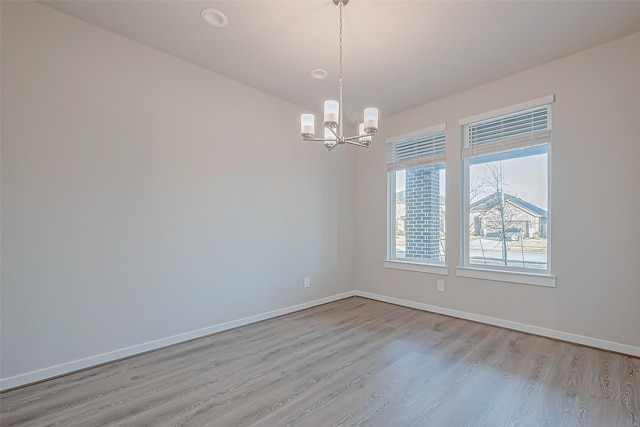 unfurnished room featuring a chandelier and light hardwood / wood-style flooring