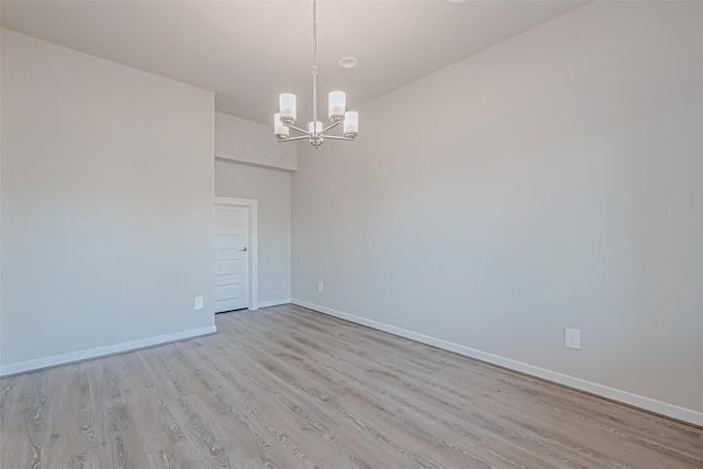 unfurnished room featuring an inviting chandelier and light hardwood / wood-style floors