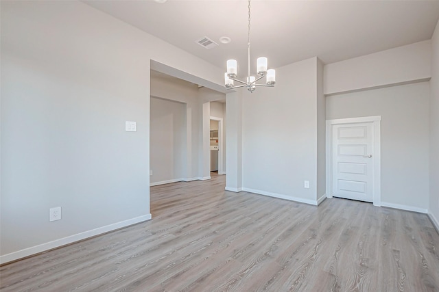 unfurnished room with light hardwood / wood-style flooring and a notable chandelier