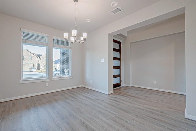 empty room featuring an inviting chandelier and light hardwood / wood-style flooring