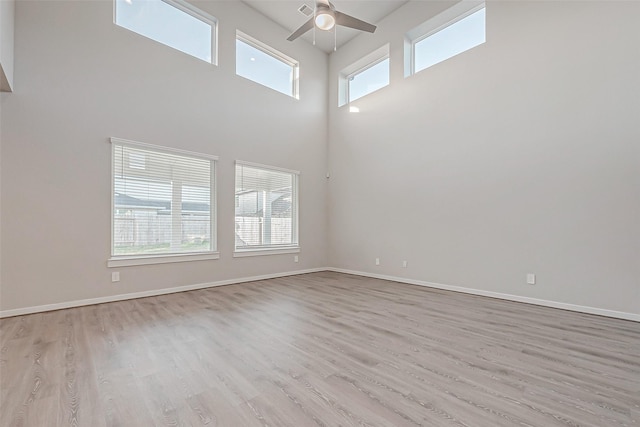 interior space with a high ceiling, ceiling fan, and light hardwood / wood-style flooring