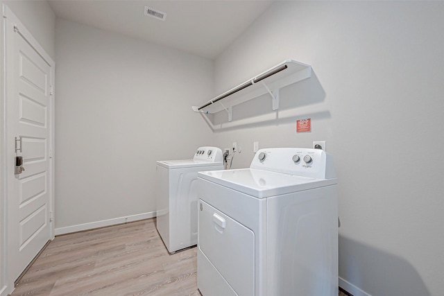 washroom featuring washing machine and clothes dryer and light hardwood / wood-style floors