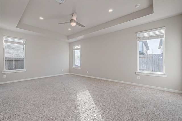 carpeted empty room with a tray ceiling and ceiling fan