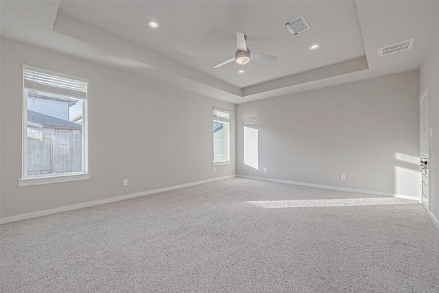 carpeted empty room with ceiling fan and a tray ceiling