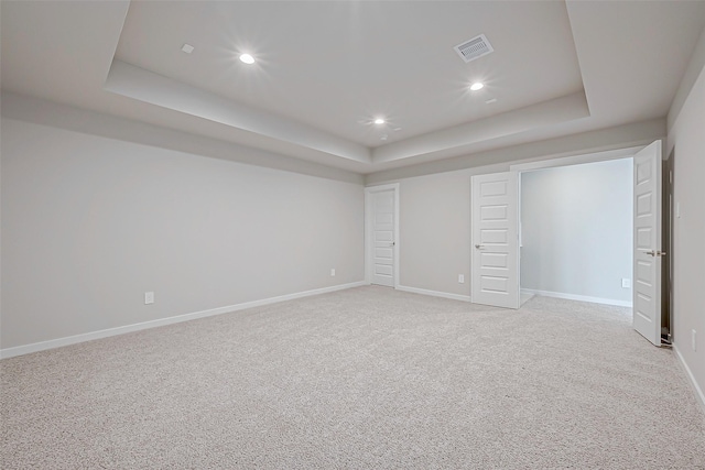 unfurnished bedroom with a tray ceiling and light colored carpet