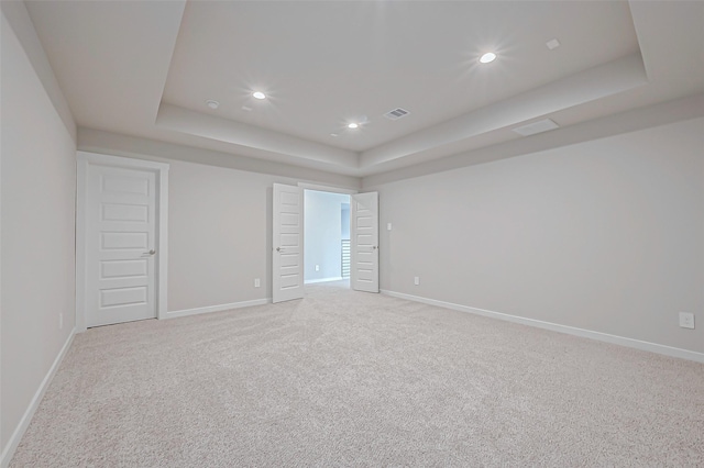 carpeted spare room with a tray ceiling