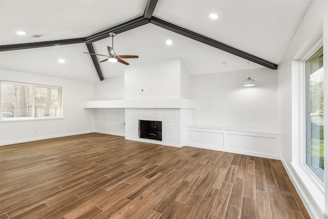 unfurnished living room with ceiling fan, vaulted ceiling with beams, hardwood / wood-style floors, and a fireplace