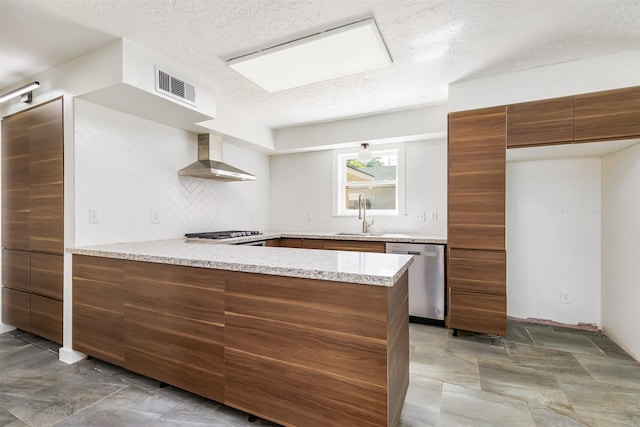 kitchen featuring sink, tasteful backsplash, kitchen peninsula, stainless steel appliances, and wall chimney range hood