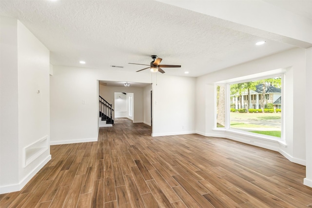 unfurnished living room with ceiling fan, wood-type flooring, and a textured ceiling