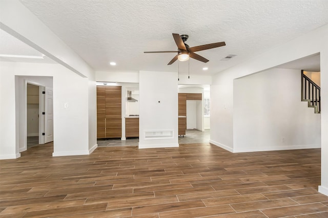 unfurnished living room featuring ceiling fan, dark hardwood / wood-style flooring, and a textured ceiling