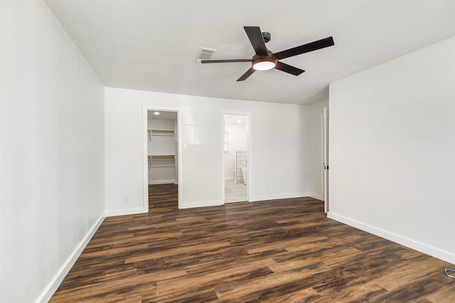 unfurnished bedroom featuring connected bathroom, a walk in closet, ceiling fan, dark wood-type flooring, and a closet