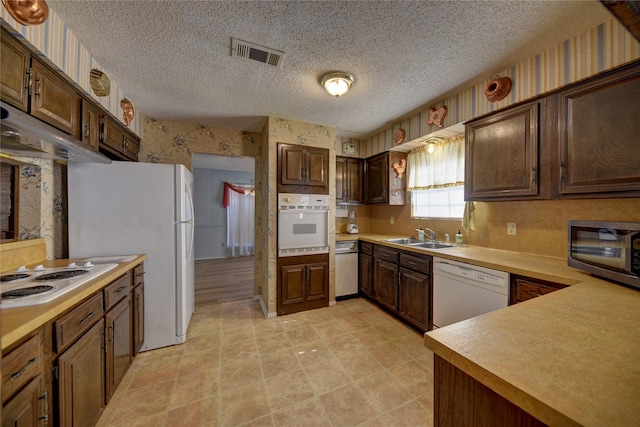 kitchen featuring light tile patterned flooring, white appliances, sink, and a textured ceiling