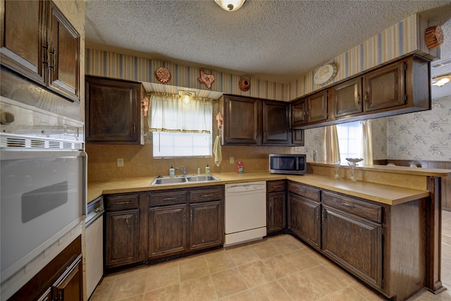 kitchen featuring sink, white appliances, dark brown cabinets, and a textured ceiling