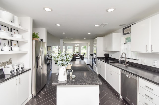 kitchen featuring stainless steel appliances, white cabinetry, a kitchen island, and sink