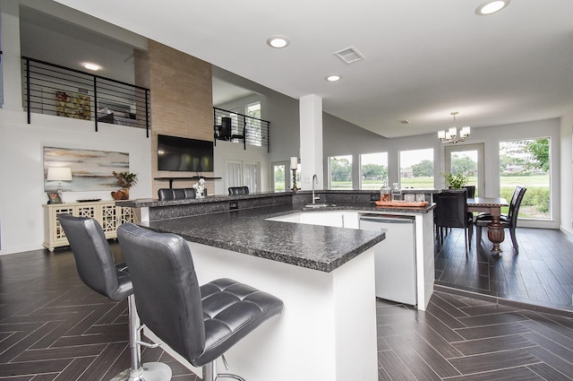 kitchen featuring a breakfast bar, dishwasher, hanging light fixtures, a notable chandelier, and kitchen peninsula