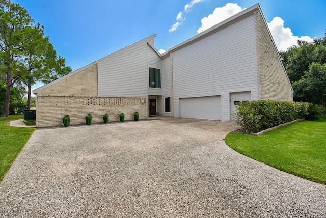 view of front of property with a garage, a front yard, and central air condition unit