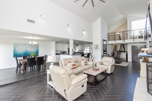 living room with a notable chandelier, high vaulted ceiling, and a healthy amount of sunlight