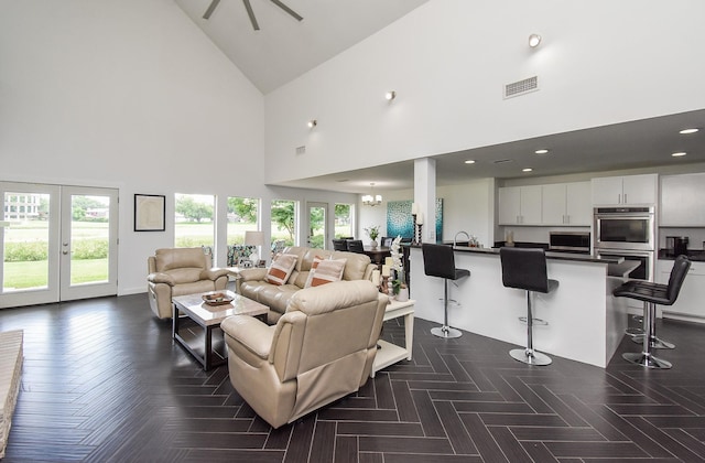 living room featuring french doors, dark parquet flooring, high vaulted ceiling, and a notable chandelier