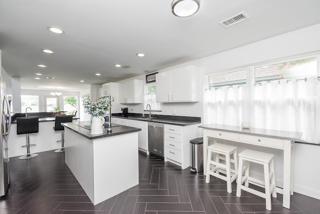 kitchen with sink, appliances with stainless steel finishes, a center island, white cabinets, and a chandelier