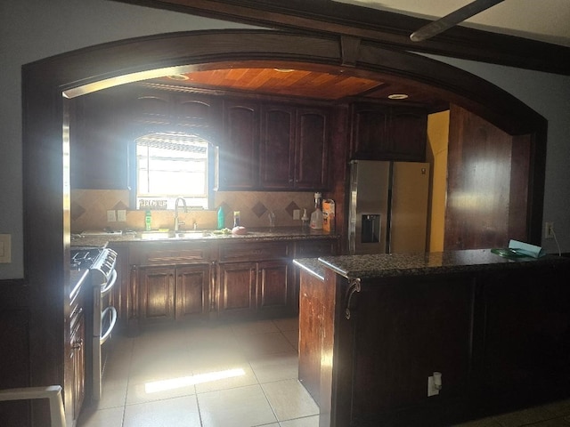 kitchen with stainless steel appliances, light tile patterned flooring, dark brown cabinetry, and decorative backsplash