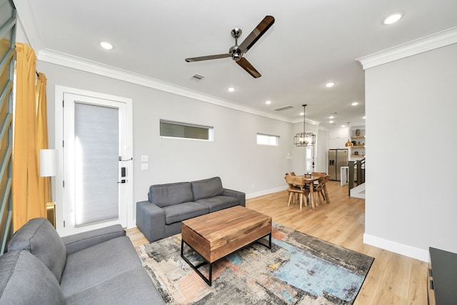 living room featuring ornamental molding, ceiling fan with notable chandelier, and light wood-type flooring