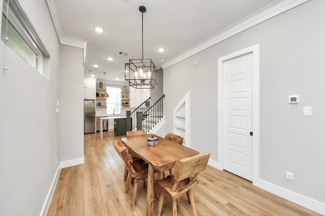 dining room featuring sink, crown molding, light hardwood / wood-style floors, and a chandelier