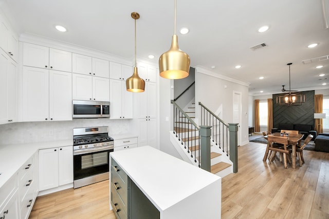 kitchen featuring pendant lighting, white cabinetry, appliances with stainless steel finishes, and a center island