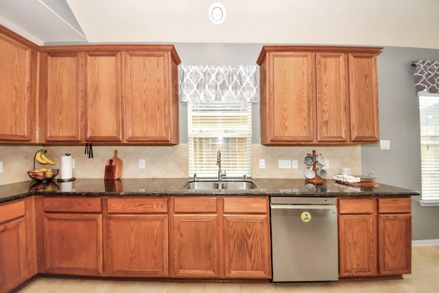 kitchen featuring a wealth of natural light, dishwasher, sink, backsplash, and dark stone counters