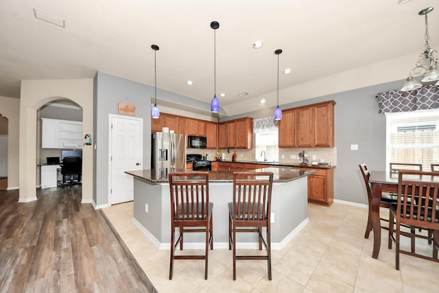 kitchen with a kitchen island, decorative light fixtures, sink, a kitchen bar, and black appliances