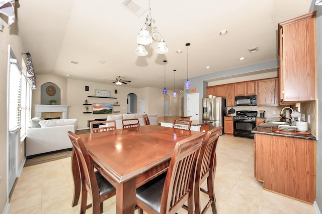 dining room featuring vaulted ceiling, sink, ceiling fan with notable chandelier, and light tile patterned floors