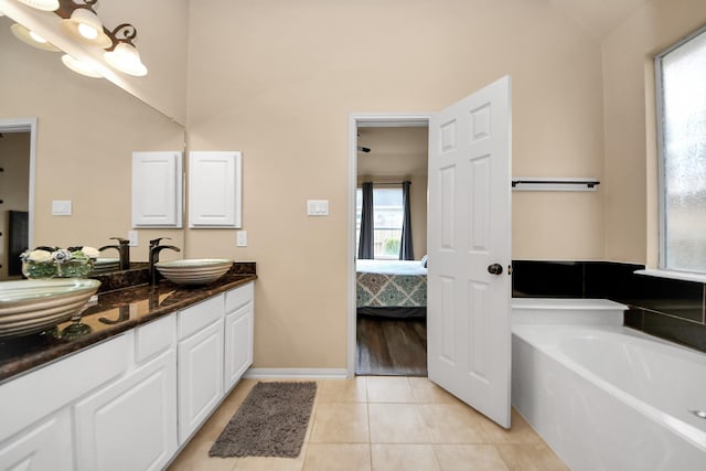 bathroom with a tub to relax in, tile patterned floors, vanity, and plenty of natural light