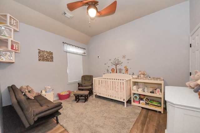 bedroom featuring a nursery area, ceiling fan, and dark hardwood / wood-style floors