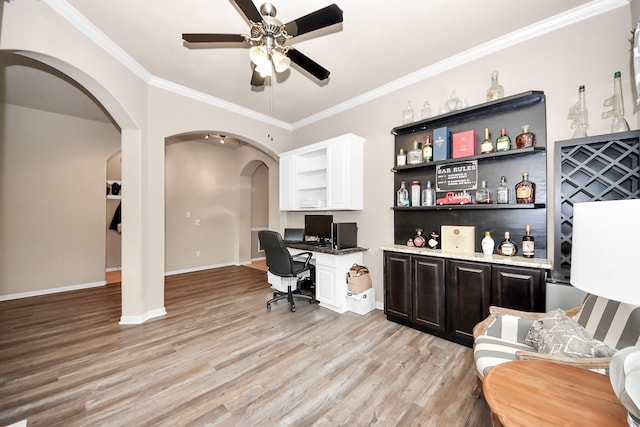 office featuring crown molding, built in desk, light hardwood / wood-style floors, and ceiling fan