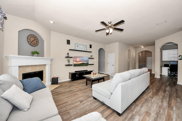 living room with hardwood / wood-style flooring, ceiling fan, and a fireplace